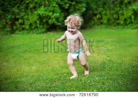 Funny Little Baby Wearing A Diaper Running In The Garden On A Hot Summer Day