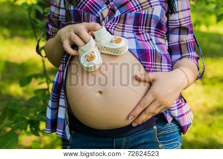 Pregnant woman holding baby shoes