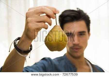 Young Man Holding A Ripe Yellow Pear