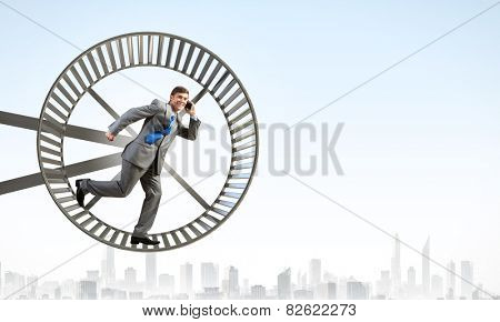 Young businessman running in huge hamster wheel