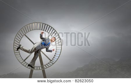 Young businessman running in huge hamster wheel