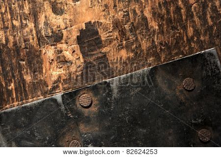 Old metal fastener on wood. Black piece of fastening iron nailed on to a grungy old wood. Focus is on center nail.