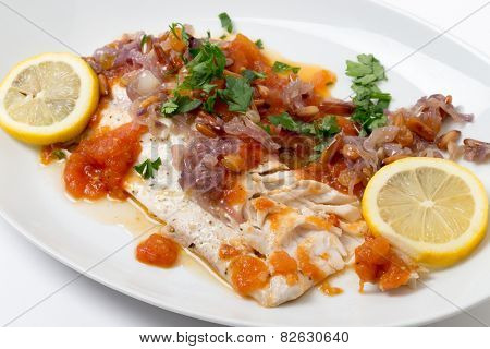 Baked fish in tomato sauce with onion and pine nut garnish, a traditional Near Eastern dish from Lebanon/Syria/Jordan