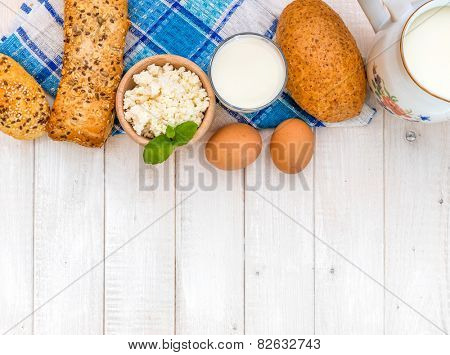 Breakfast of cheese, milk, bread and eggs on a light wooden background
