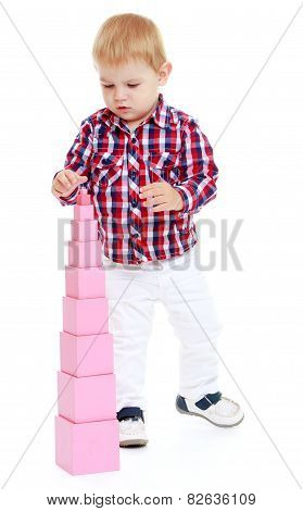 very small boy collects Red Pyramid in the Montessori classroo