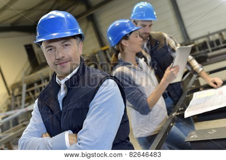Supervisor in factory with employees in background