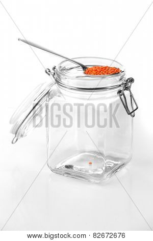 Remnants of lentils in spoon with glass jar isolated on white