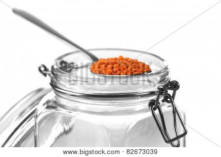 Remnants of lentils in spoon with glass jar isolated on white