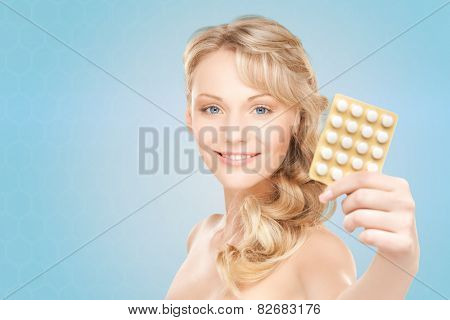 people, beauty, healthcare and medicine concept - happy young woman holding package of pills over blue background