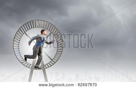 Young businessman running in huge hamster wheel