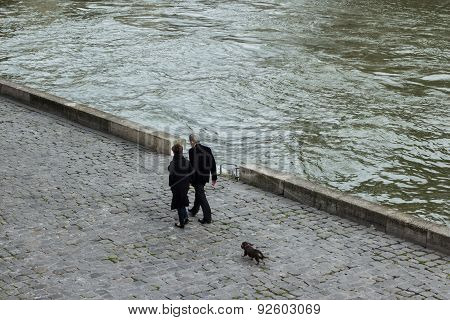 Couple walk their dog along river Seine, Paris
