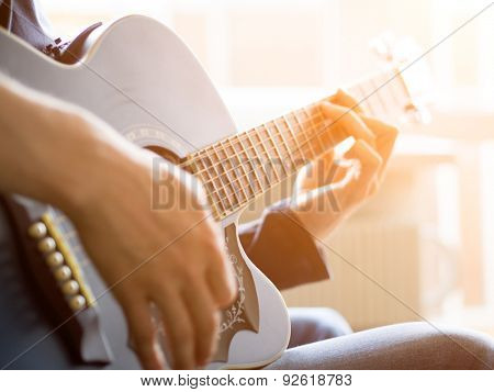 Male hand playing on acoustic guitar. Close-up. Sunflare
