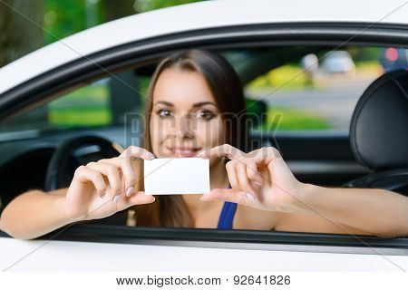 Attractive woman inside car showing card