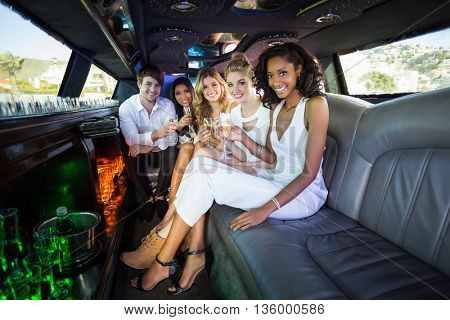 Happy friends drinking champagne in limousine