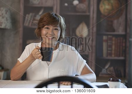 asian woman smiling face happiness emotion and coffee cup in hand sitting on wood table at home