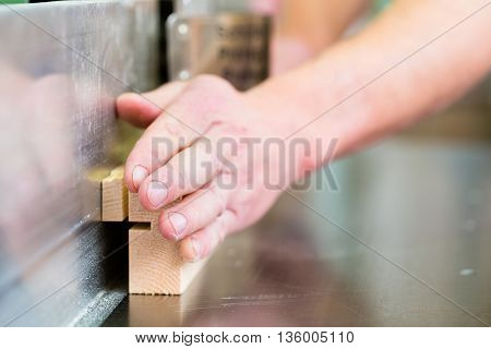 Carpenter working on an electric buzz saw or wood milling and cutting some boards in carpentry