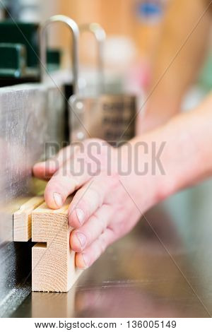 Carpenter working on an electric buzz saw or wood milling and cutting some boards in carpentry