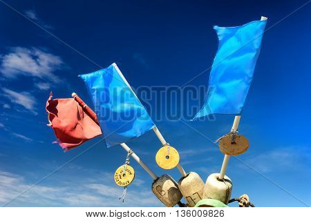 Red and blue flags on floats fishing nets on the shore of the Baltic Sea on a sunny summer day against the blue sky with clouds