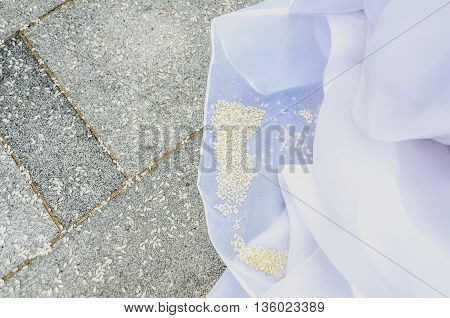 Detail of brides wedding dress with rice on the floor. Pavement full of rice after a wedding ceremony.
