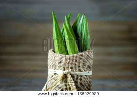A heap of raw okra or Lady's fingers or gumbo in a bag on wooden background
