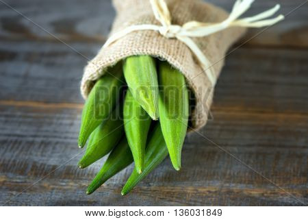 A heap of raw okra or Lady's fingers or gumbo in a bag on wooden background
