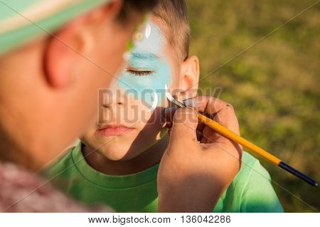 Woman does greasepaint on the child's face