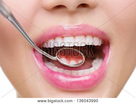 Healthy white woman teeth and a dentist mouth mirror closeup. Isolated on a white background. Dental hygiene, oral care concept