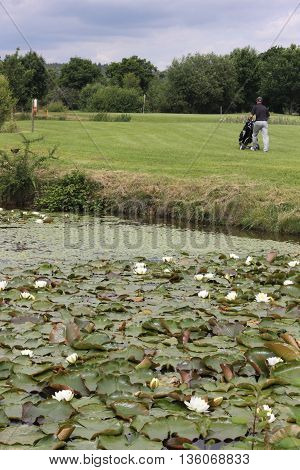 A golfer walking to the green on a par 3 with water in the foreground