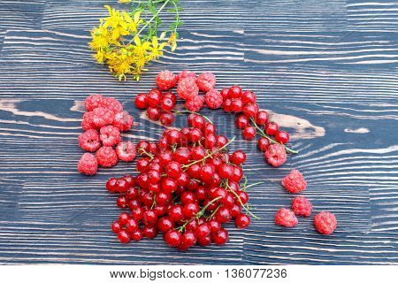 Ripe fresh clusters of red currant and raspberry on the table