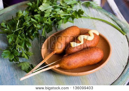 corndog sausage on a stick with mustard, ketchup and parsley