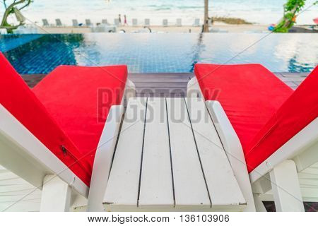 Beautiful beach chairs with umbrella around outdoor swimming pool neary sand and sea