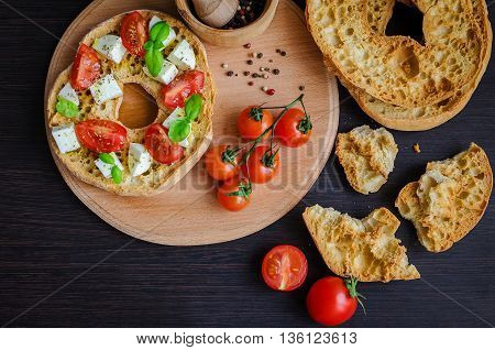 Italian appetizer Friselle. Italian dried bread Friselle on wooden board with tomatoes cherry basil and pepper. Italian food. Healthy vegetarian food. A quick and easy snack for party time.