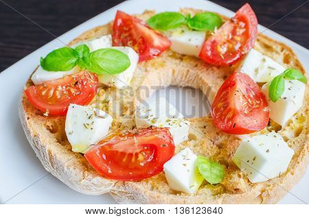 Italian starter friselle. Classical frisella tomato cheese mozzarella and basil with oregano and olive oil. Dried bread called freselle on white plate. Italian food. Healthy vegetarian food.