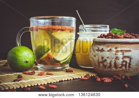 Fresh antioxidant herbal tea from goji berries lime and honey in a glass cup. Wolfberry for a healthy diet. Healthy food. Alternative medicine. Recovery. Rejuvenation. Slimming. Mystic light style.