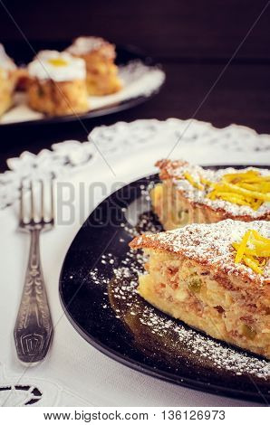 Torta di riso. Baked rice pudding dessert sweetened with sugar powder and garnished with candied orange peels in the top with a fork on the side. Rice cake with almonds and amaretto. Selective focus.