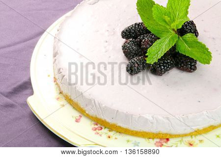 Homemade violet mulberry cheesecake with ment on violet board.
