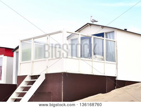Beach huts or houses and blue sky. Multicolored beach bathing huts with white sand and clear blue sky. Beach scene with copy space. Side view of beach huts in a row.