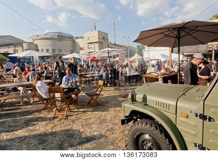 KYIV, UKRAINE - JUN 4, 2016: Big food-court with tables and people eating meals under umbrelas outdoor during city fair on June 4, 2016. Kiev is the 8th most populous city in Europe.