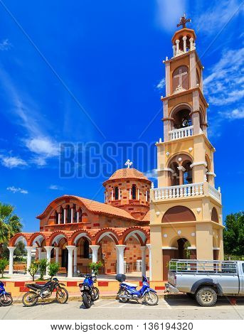 Beautiful orange Greek church on the island of Rhodes. The bright sky with clouds