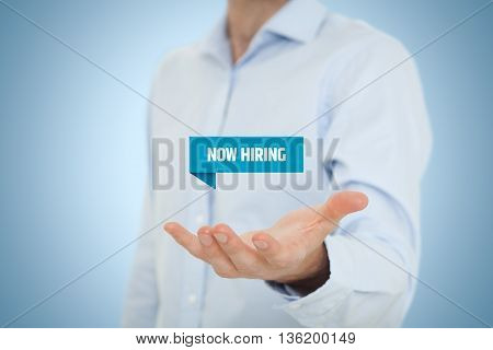 Businessman (recruiter or HR staffer) hold virtual label with text now hiring - human resources concept..