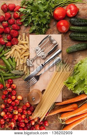 Italian food background, with vine tomatoes, basil, spaghetti, mushrooms, olives, parmesan, olive oil, garlic, peppercorns, rosemary, parsley and thyme. Slate background.
