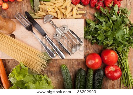 Italian food background, with vine tomatoes, basil, spaghetti, mushrooms, olives, parmesan, olive oil, garlic, peppercorns, rosemary, parsley and thyme. Slate background.