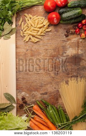 Italian food background, with vine tomatoes, basil, spaghetti, mushrooms, olives, parmesan, olive oil, garlic, peppercorns, rosemary, parsley and thyme. Slate background.