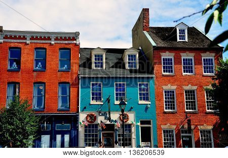 Baltimore Maryland - July 22 2013: 18th and 19th century brick buildings lining the historicThames Street waterfront now house trendy shops pubs and restaurants at Fells Point