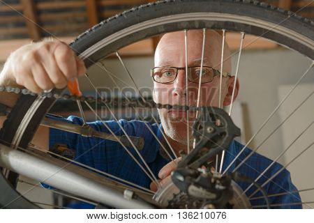 a man repairing bicycle in his workshop.