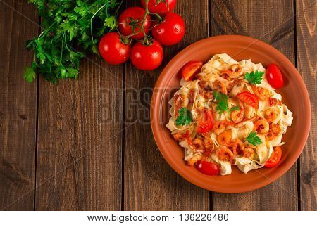 Fettuccine pasta with shrimp tomatoes and herbs. wooden background. Top view