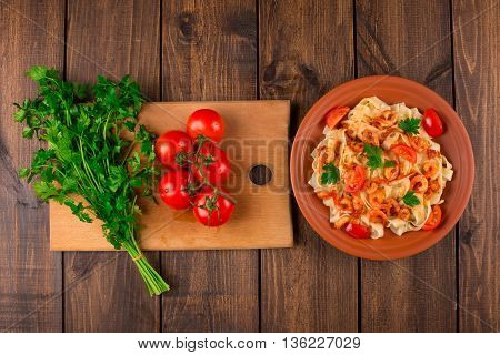 Fettuccine pasta with shrimp tomatoes and herbs. wooden background. Top view