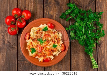 Fettuccine pasta with shrimp tomatoes and herbs. wooden background. Top view
