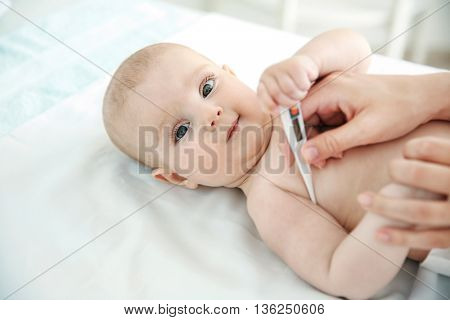 Doctor taking baby's temperature, close up