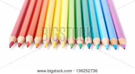 Multiple colorful color pencils composition arranged in a line to form a rainbow gradient, composition isolated over the white background, close-up crop fragment
